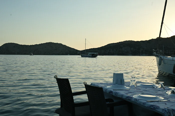 Alacakaranlıkta sakin bir koya bakan iskelede kurulmuş akşam yemeği masası